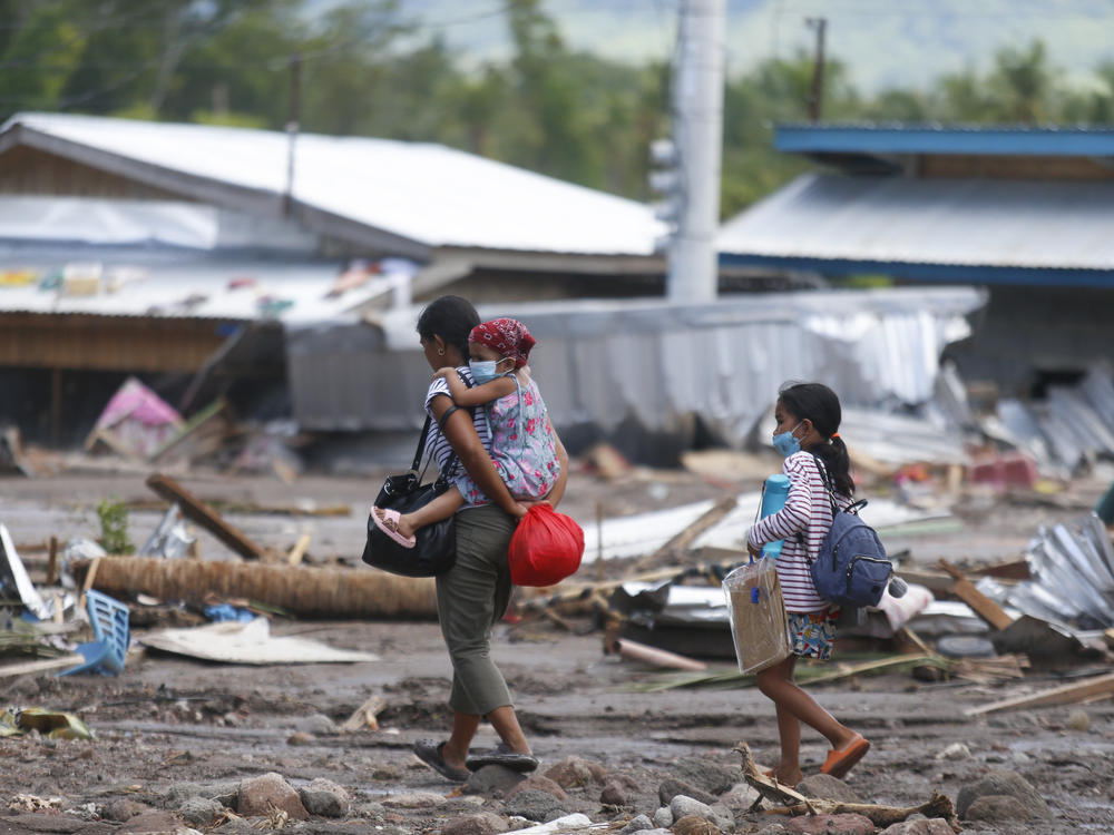 Residents walk beside remains of damaged homes at Maguindanao's Datu Odin Sinsuat town.