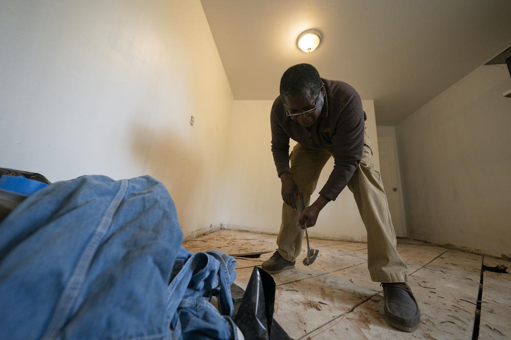 A contractor for The Port repairs a saggy wood floor that's rotted through in places. The home had been vacant for about a year and is thought to have flooded after pipes froze.