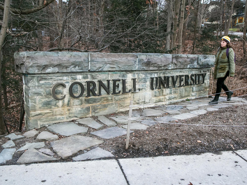 A woman walks by a Cornell University sign on the Ivy League school's campus in Ithaca, N.Y.