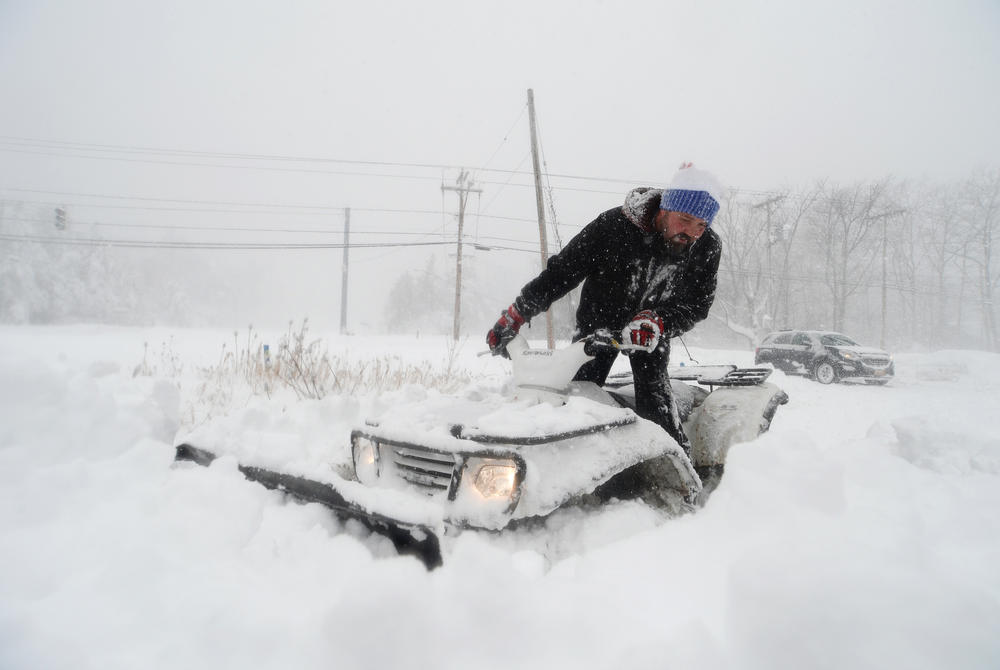 Robert Skimin uses an ATV to dig out after an intense snowstorm.