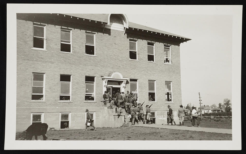 Soldiers of the 57th Infantry of the 3rd Division from Camp Pike in Little Rock carry rifles as they enter a guardhouse and hospital after being dispatched to Elaine in 1919.