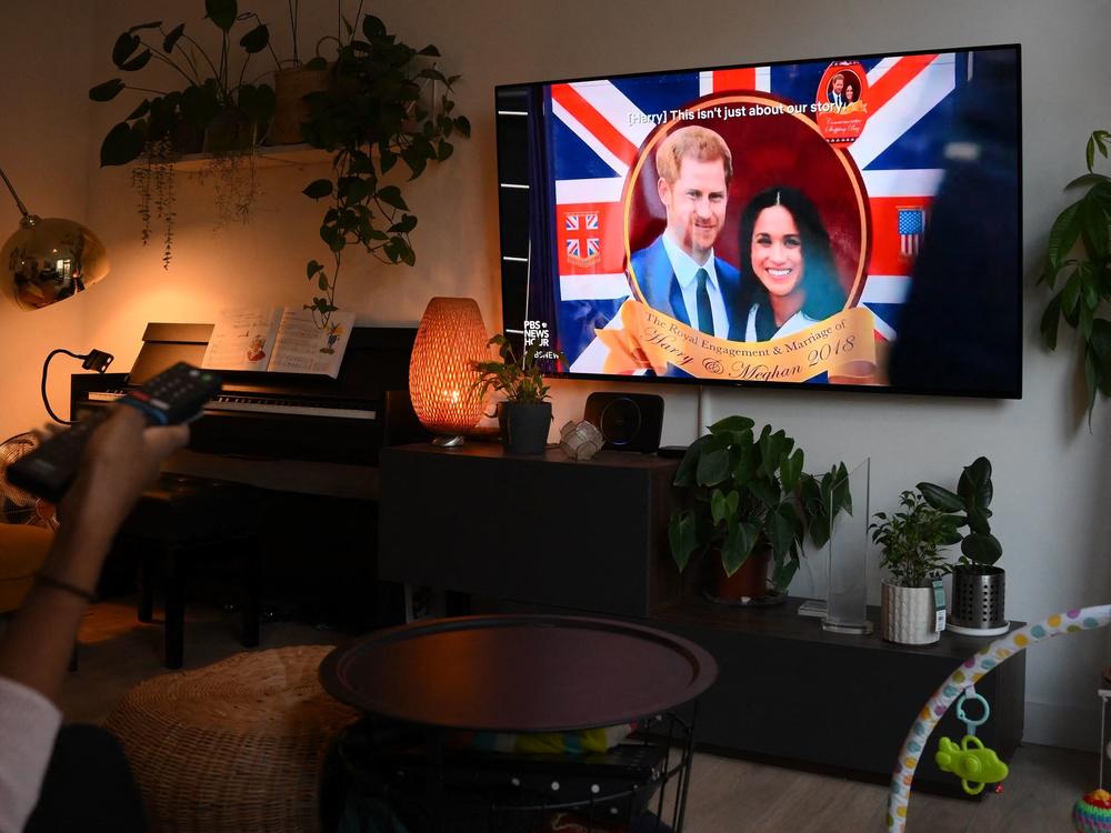 A woman watches an episode of the newly released Netflix docuseries <em>Harry & Meghan,</em> about Britain's Prince Harry, Duke of Sussex, and Britain's Meghan, Duchess of Sussex, in London on Thursday.