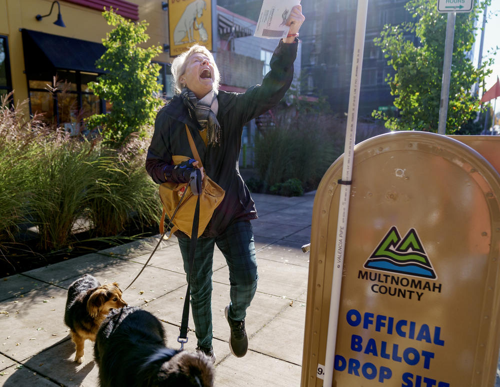Perrin Thompson kisses her ballot for luck and does a little dance before dropping it into a drop site outside of the Multnomah County Elections Division in Portland, Ore., Nov. 8, 2022. Full story <a href=