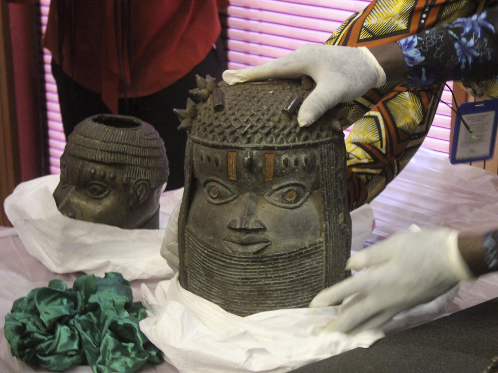Looted Benin Bronzes that were returned by Germany to Nigeria are examined during a ceremony in Abuja on Tuesday. Nigerian officials said that more than 5,000 ancient artifacts are estimated to have been stolen from Nigeria, the majority by British colonizers.