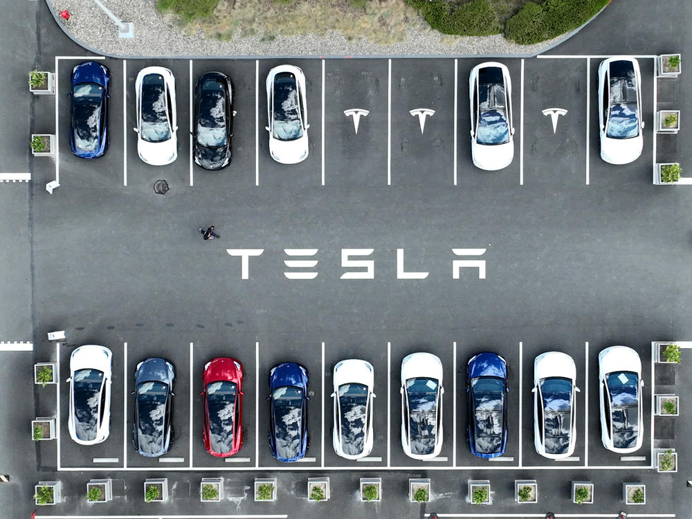 In an aerial view, Tesla cars sit parked in a lot at the Tesla factory in Femont, Calif., on April 20, 2022.