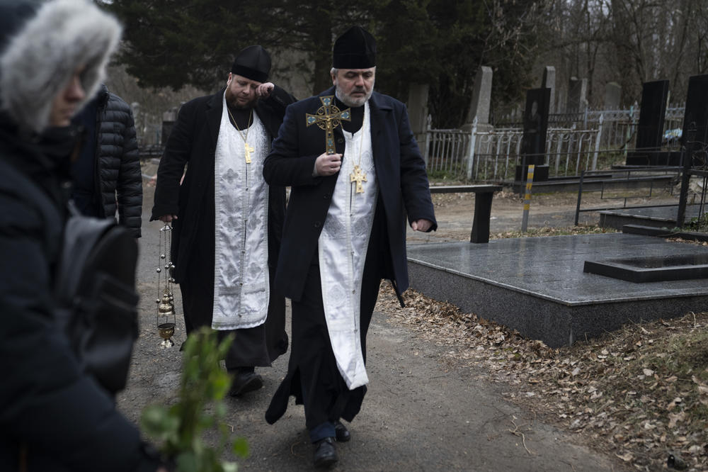 Priests walk through the cemetery as mourners gather for Korenovsky's funeral.