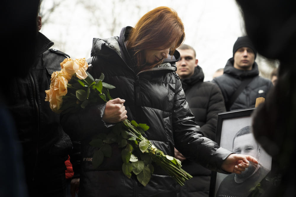 Korenovsky's wife, Olha Korenovska, touches a portrait of her husband at the funeral.