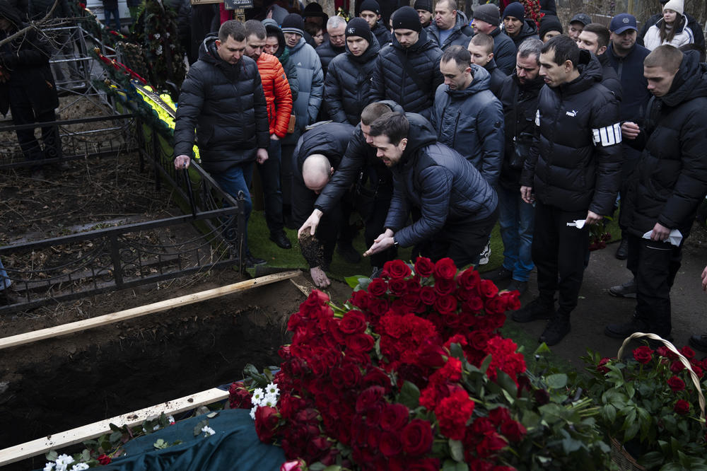 Mourners throw soil into the grave over Korenovsky's coffin.