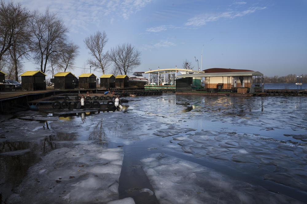 Ice in the Dnipro River gathers in front of a recreational area that stands empty in the winter.