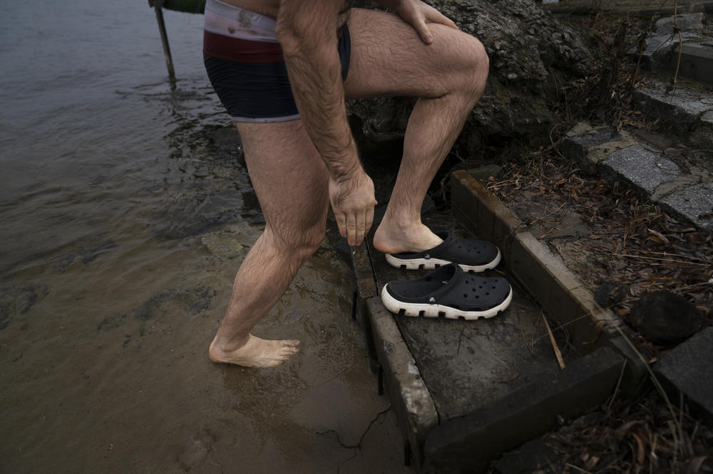 Pastuchenko slips his shoes back on after taking the plunge into the Dnipro River on Thursday.