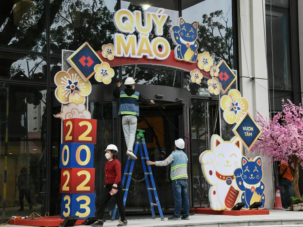 People work on a display of cat figures at a building entrance in Hanoi on Monday.