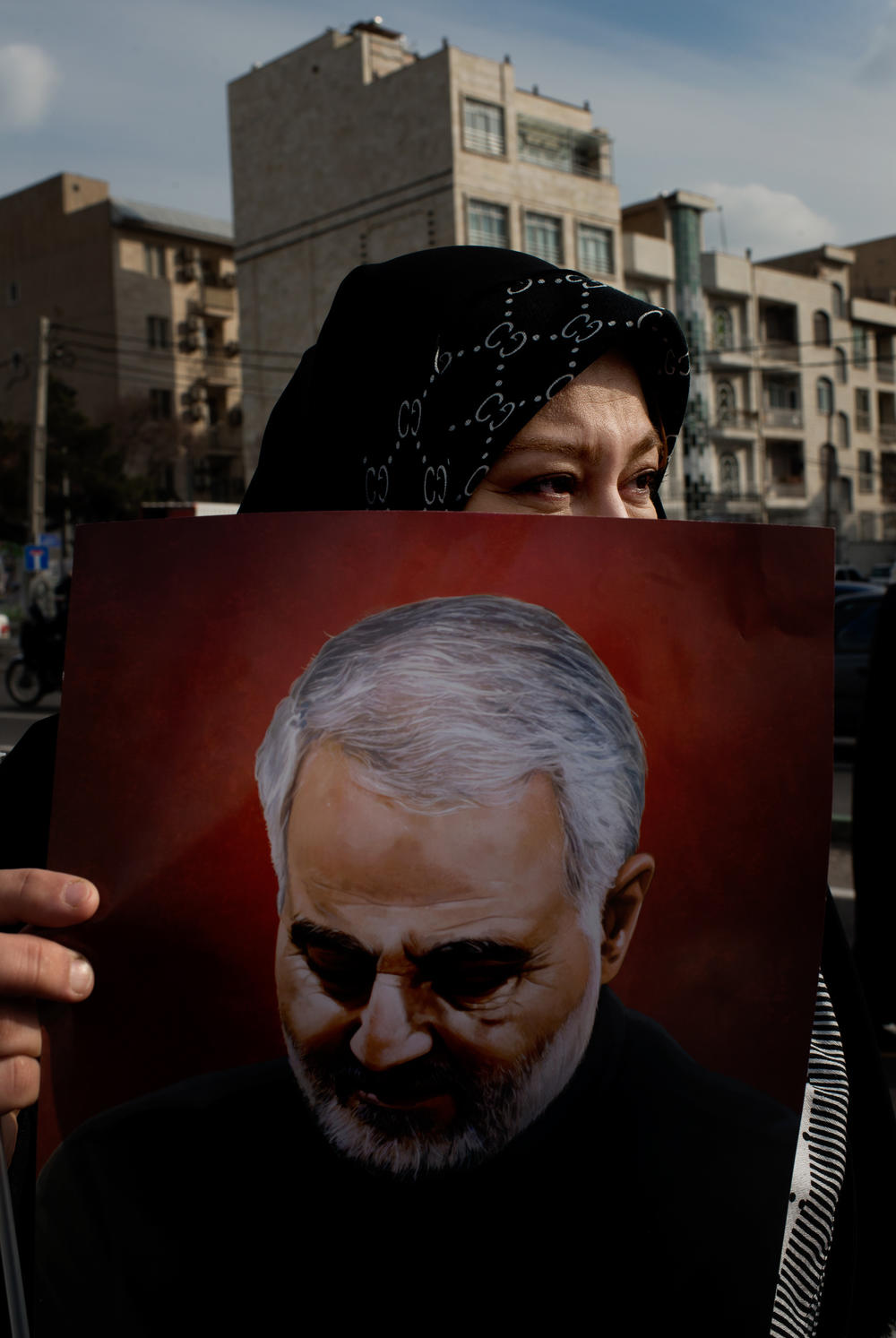 A woman holds a photo of Qasem Soleimani, an Iranian military commander who served in the Islamic Revolutionary Guard Corps.