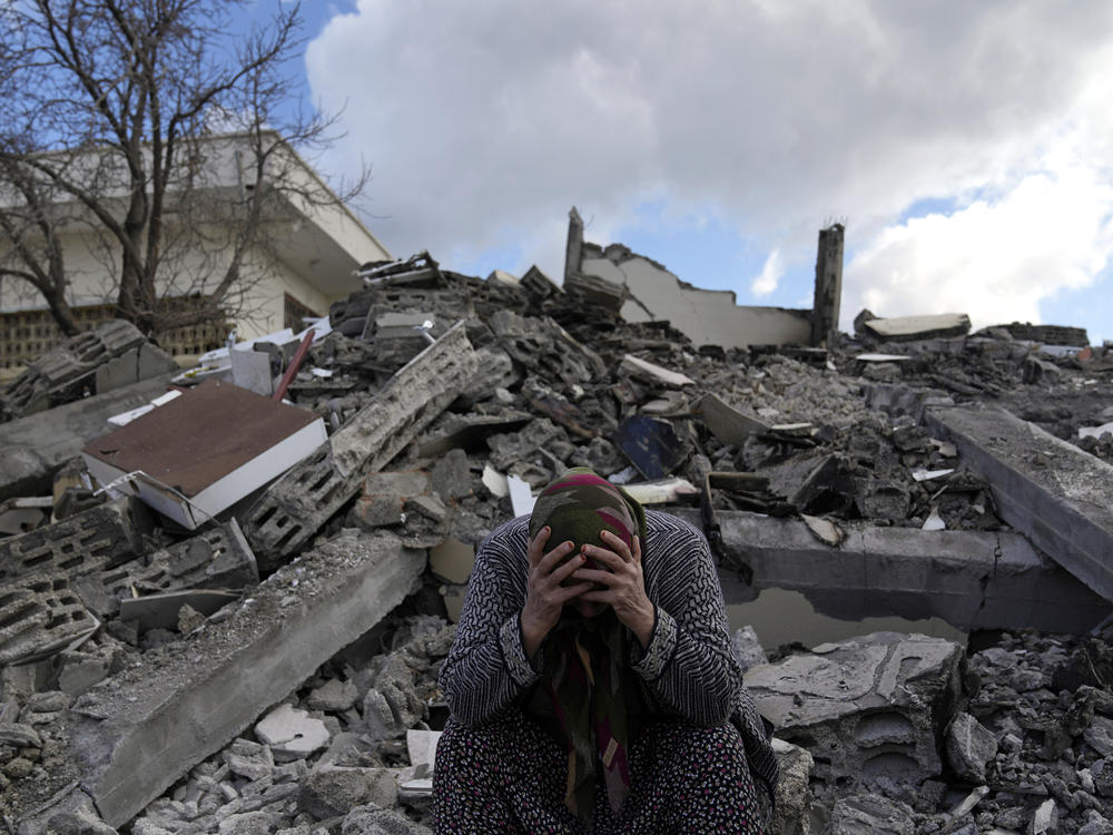 A woman sits on the rubble as emergency rescue teams search for people under the remains of destroyed buildings in Nurdagi town on the outskirts of Osmaniye city southern Turkey, on Feb. 7. Now, nearly a week later, many people in Osmaniye are still living in tents and other makeshift shelters.