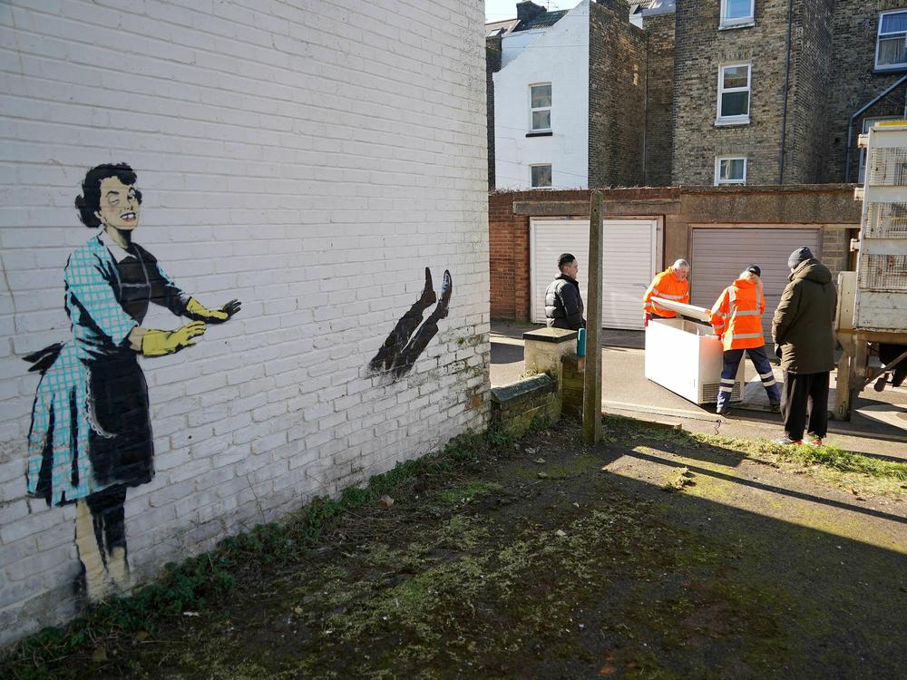 Workers remove a chest freezer that was part of an artwork by street artist Banksy, along the side of a house in Margate, southeast England.