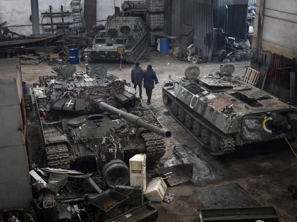 Mechanics pass a captured Russian T-72B3 tank (left) and a MT-LB armored vehicle to be repaired and used by Ukrainian forces on Feb. 13 at a warehouse in eastern Ukraine.