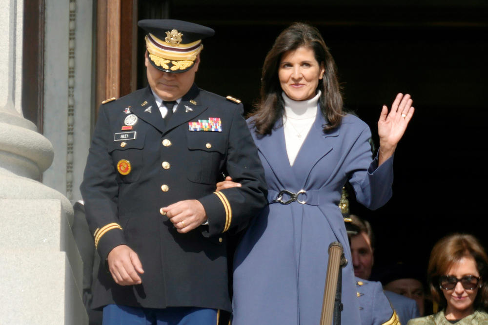 Former South Carolina Gov. Nikki Haley, right, waves as she and her husband, Michael Haley, left, are introduced at the second inaugural of Gov. Henry McMaster on Wednesday, Jan. 11, 2023, in Columbia, S.C. As governor, Haley signed the bill to remove the Confederate flag from state Capitol grounds.