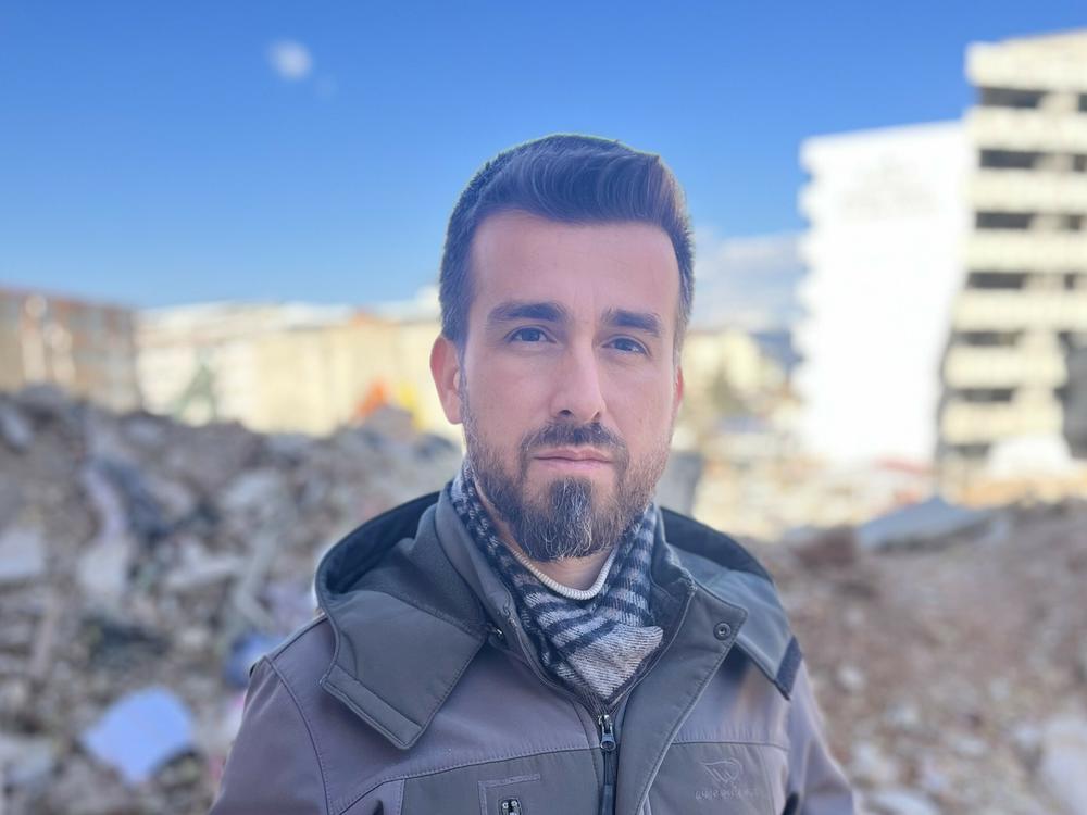Ali Kafadenk, 34, poses in front of the rubble of his destroyed apartment in Islahiye, Turkey. He and his wife Merve, 27, survived the earthquake that struck Turkey and Syria on Feb 6.