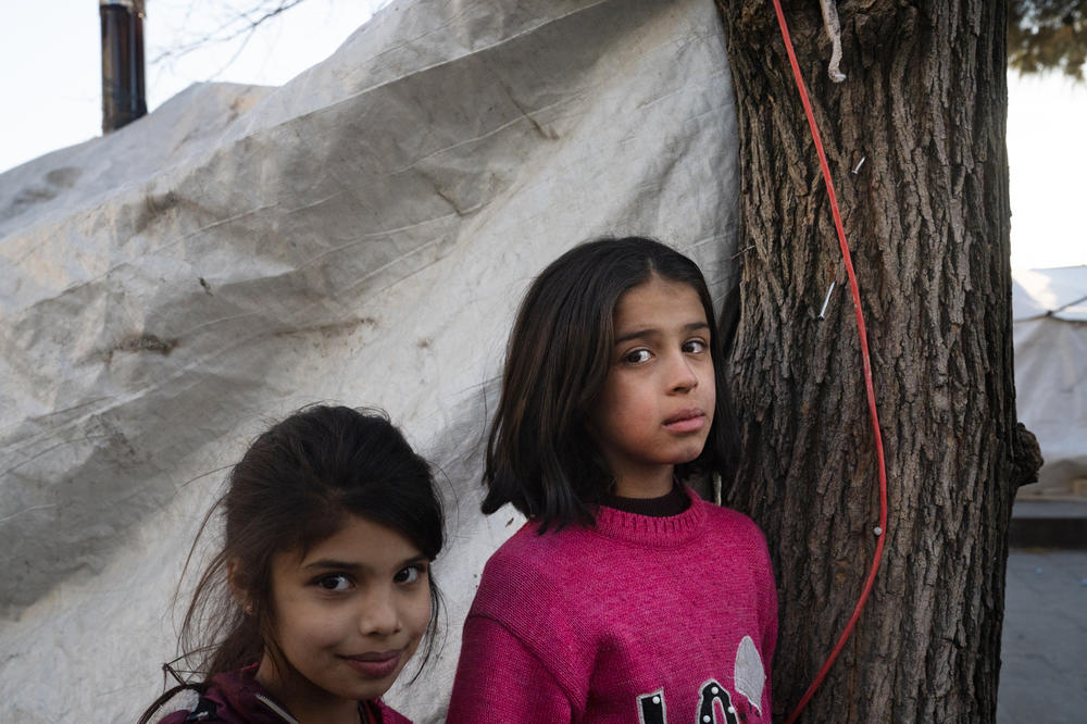 Emine Kader, 10 (right), and her younger sister stand in front of a tent in the encampment where they are staying in Gaziantep.