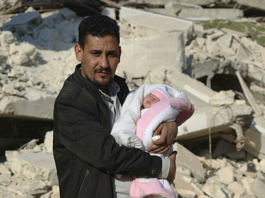 Khalil al-Sawadi holds Afraa, a baby girl who was born under the rubble caused by an earthquake that hit Syria and Turkey, on Monday in the town of Jinderis, Aleppo province, Syria.