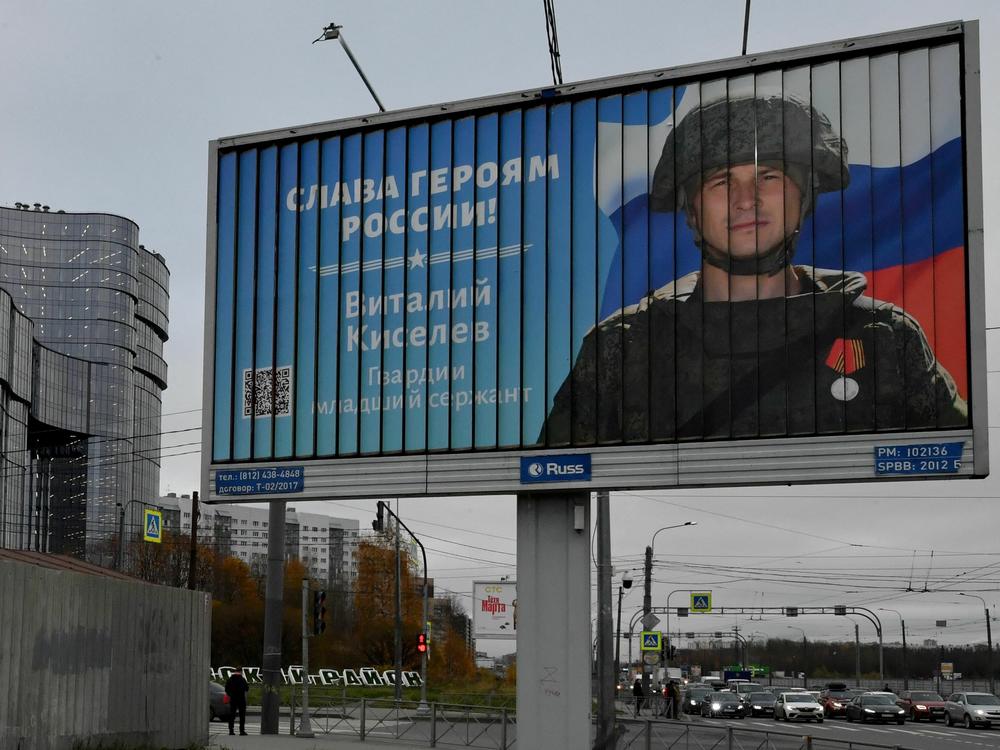 A poster displays a Russian soldier with a slogan reading 