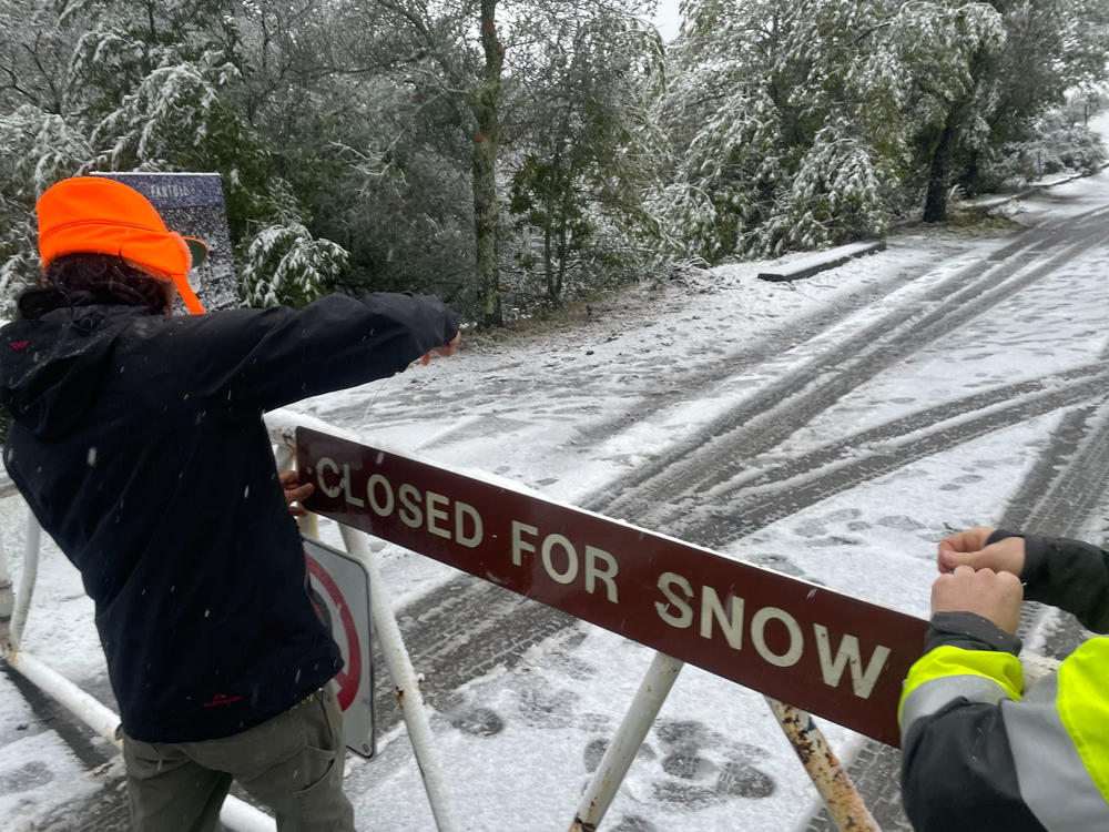 A parks worker puts up a closed sign at the entrance to Mount Tamalpais State Park in Mill Valley, Calif., Friday Feb. 24, 2023.