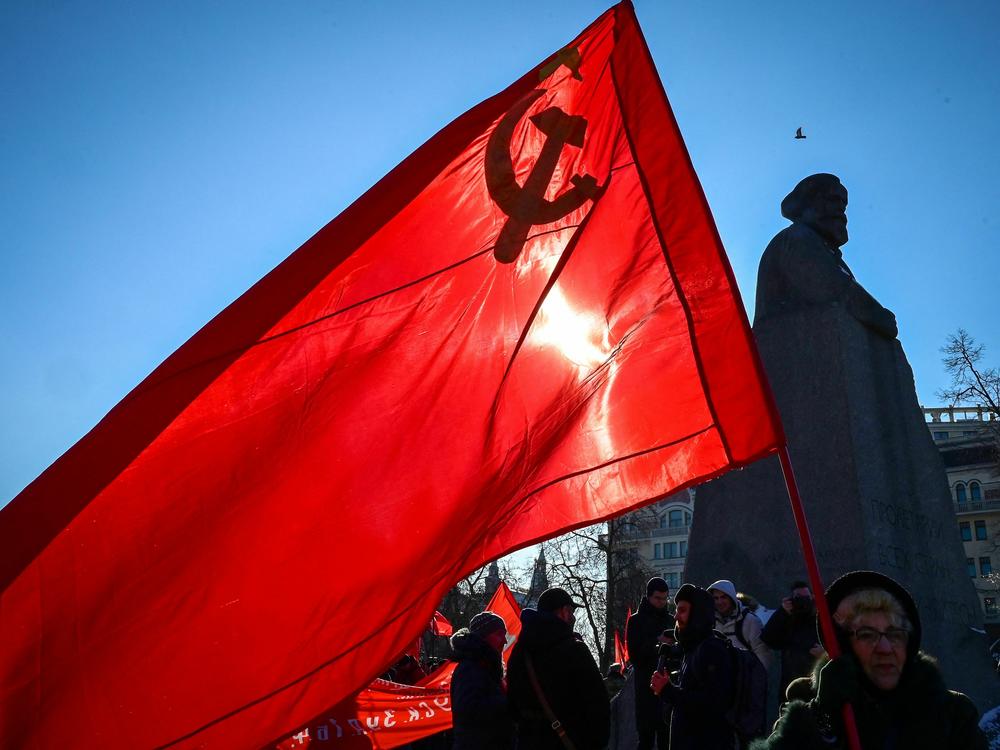 Russian Communist supporters hold flags including one of the Soviet Union, as they take part in a rally next to the Karl Marx monument, marking the 