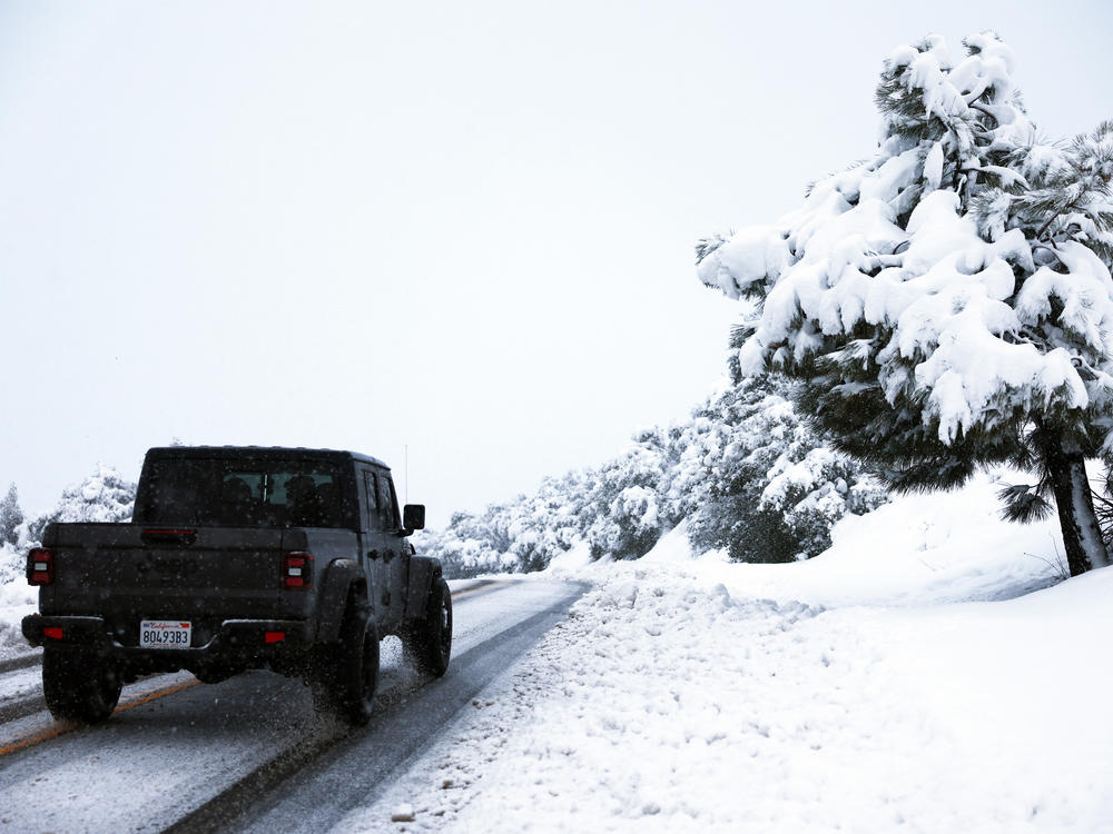 A person drives along a snowy roadway in Los Angeles County, in the Sierra Pelona Mountains, on Saturday near Green Valley, Calif. A major storm delivered heavy snowfall to the mountains with some snow reaching lower elevations in Los Angeles County. More is expected on Tuesday into Wednesday.