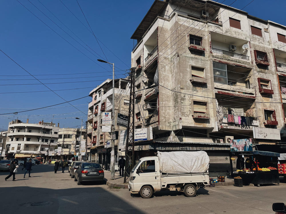 The city center of Jableh is home to older buildings as well as newer, less regulated construction. An image of President Bashar Assad hangs over a street cart with the slogan 