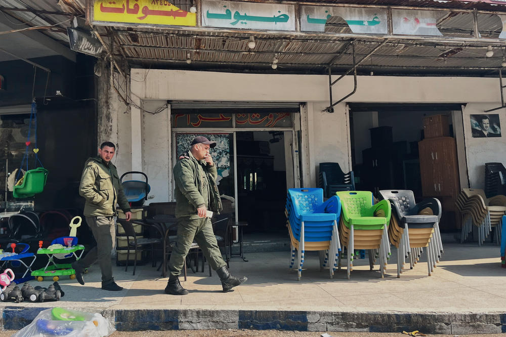 Men walk past a store in the city center of Jableh. Military service is mandatory in Syria for men and many in this region have fought in the war.