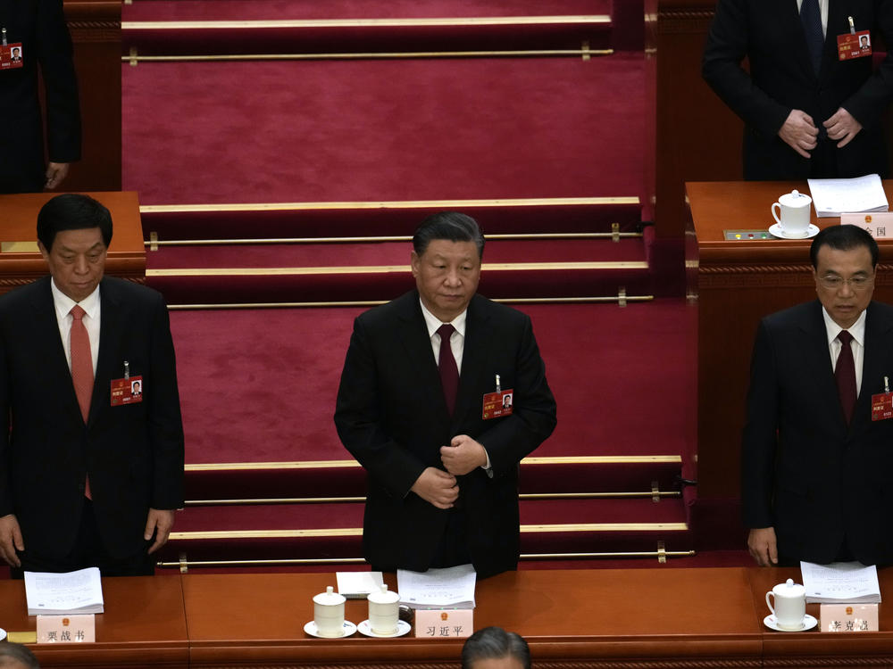 From left, Li Zhanshu, Chinese President Xi Jinping, and Premier Li Keqiang stand during the opening session of China's National People's Congress (NPC) at the Great Hall of the People in Beijing, Sunday, March 5, 2023.