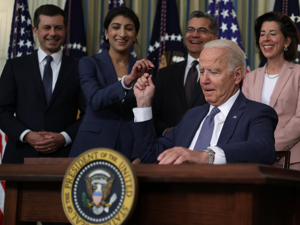 President Joe Biden passes a signing pen to Chairperson of the Federal Trade Commission Lina Khan (2nd L) at the White House on July 9, 2021. President Biden signed an executive order on 