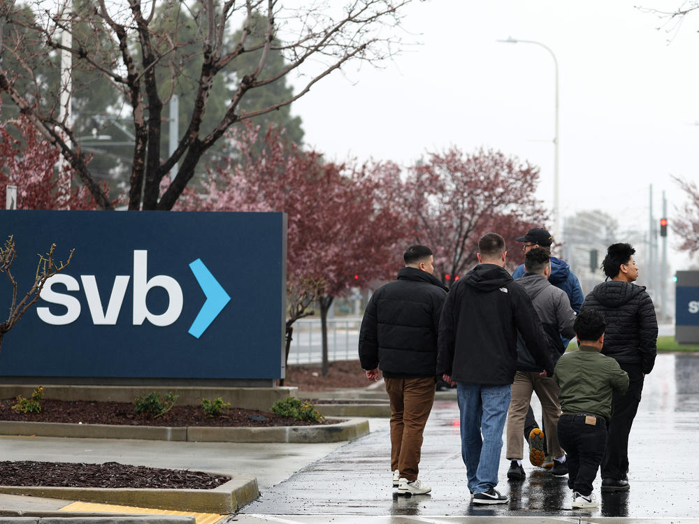 People walk through the parking lot at the Silicon Valley Bank headquarters in Santa Clara, Calif., on March 10. SVB saw a surge in deposits during the tech boom, but was forced to sell some of its bond holdings at a steep loss after seeing an increase in deposit withdrawals.