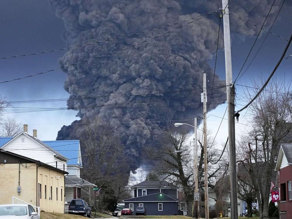 A black plume rises over East Palestine, Ohio, as a result of a controlled detonation of a portion of the derailed Norfolk Southern trains in February. The Ohio attorney general said Tuesday that the state is suing the railroad.