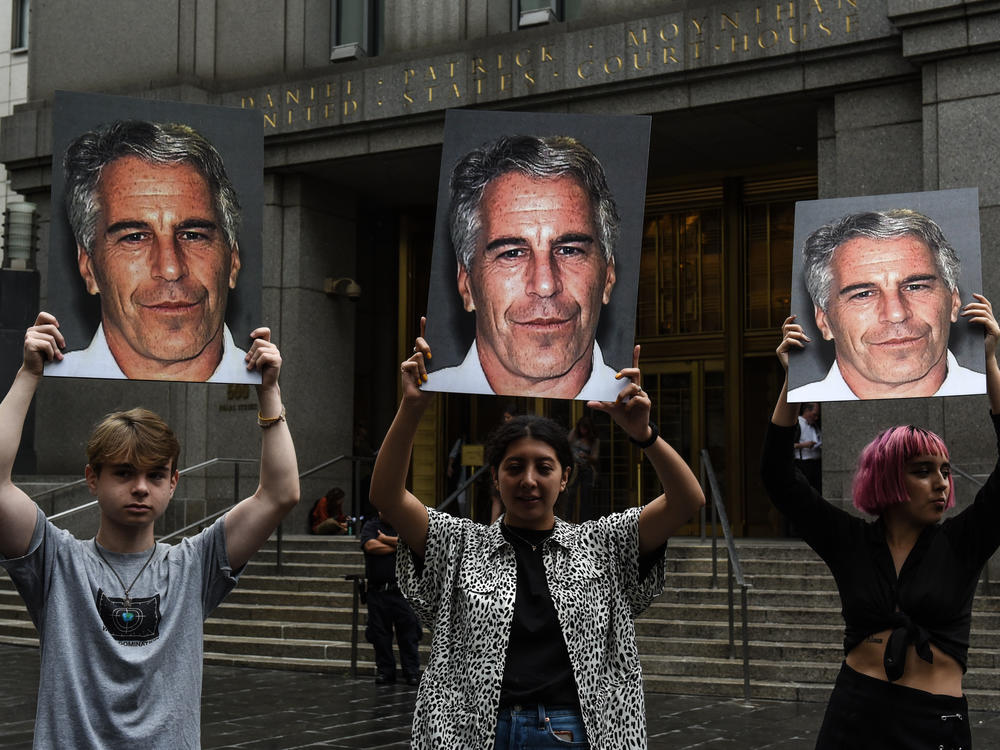 A group of protesters hold photos of Jeffrey Epstein in front of a New York City federal courthouse in July 2019. A Southern District judge ruled this week that three lawsuits against banks that Epstein used can move forward.