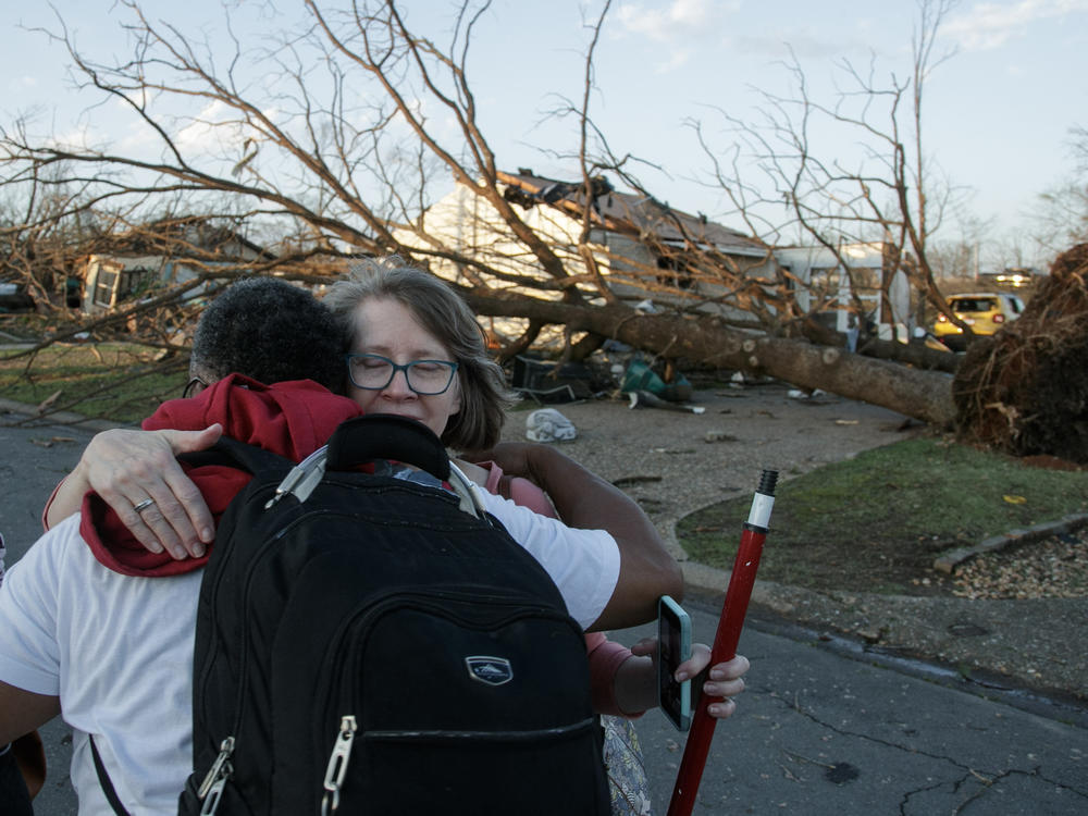Residents embrace while evacuating their neighborhood after a large tornado damaged homes and buildings on March 31 in Little Rock, Arkansas.
