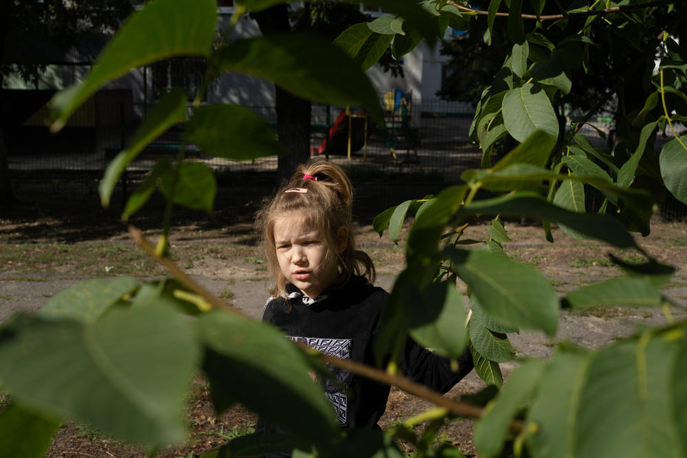 Sofiia Kuzmina gathers leaves on an empty playground in Kharkiv. Her mother, Natalia, says Sofiia has gotten used to playing by herself.