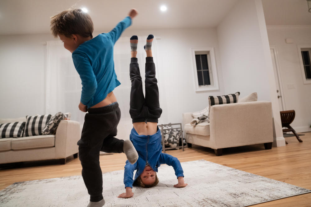 Daniel and his younger brother Adam play in the living room. Daniel has been taking break-dancing lessons and demonstrates a headstand.