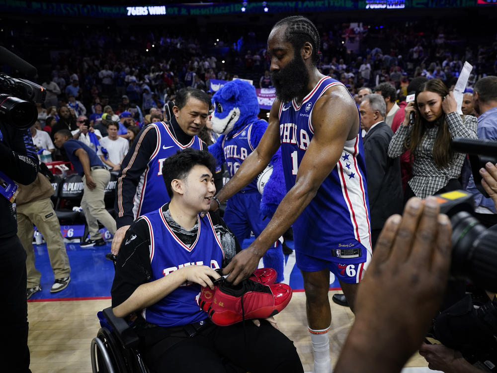Philadelphia 76ers' James Harden gives his sneakers to John Hao after Game 4 in an NBA basketball Eastern Conference semifinals playoff series, Sunday, May 7, 2023, in Philadelphia. Harden invited Hao, a student severely wounded in a Feb. 13 mass shooting at Michigan State University, to view the game.