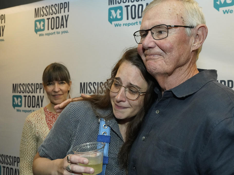 Mississippi Today reporter Anna Wolfe, center, is congratulated Monday by staff sports columnist Rick Cleveland, right, after winning the 2023 Pulitzer Prize for Local Reporting, as her mother, Bethel Wolfe, left, observes, at a celebration in Jackson, Miss. Wolfe was honored for her reporting on a $77 million welfare scandal, the largest embezzlement of federal funds in Mississippi's history.