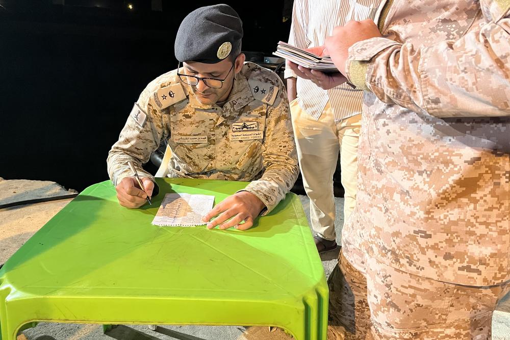 A Saudi officer checks the names of evacuees against a handwritten list in Port Sudan before they board boats and cross the Red Sea to the safety of Saudi Arabia. May 2, 2023.