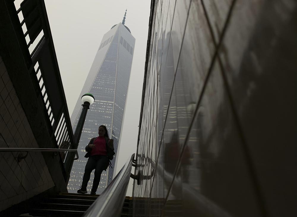 A commuter steps into the subway as smoke from wildfires in Canada partially obscure One World Trade Center in lower Manhattan, Tuesday, June 6, 2023, in New York.