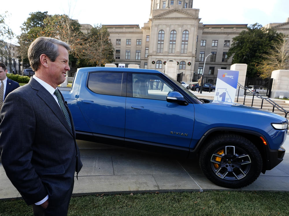 In Atlanta, Republican Gov. Brian Kemp stands next to a Rivian electric truck while announcing the company's plans to build a plant east of Atlanta, Dec. 16, 2021. Hyundai and Kia will also soon make electric vehicles in Georgia.