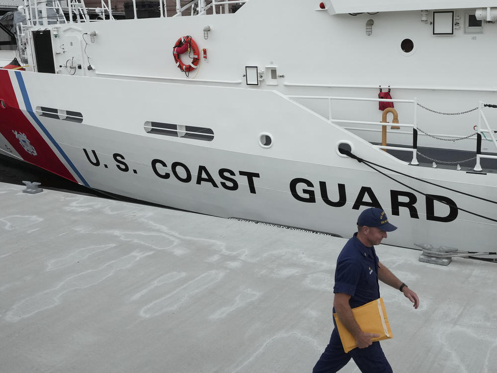 U.S. Coast Guard Cutter Warren Deyampert is docked Tuesday as a member of the Coast Guard walks past at Coast Guard Base Boston.