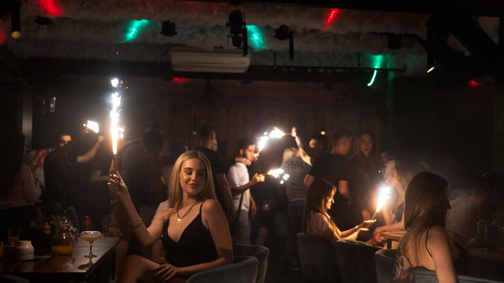 Patrons at a club in Kharkiv hold sparklers in the darkened room. Despite the ongoing war, people are still finding a way release tension in nightclubs in the the battered city.