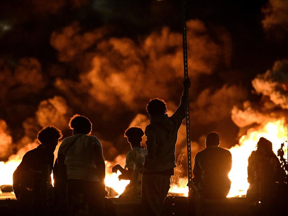 People look at burning tires blocking a street in Bordeaux in southwestern France on Thursday night, as the country saw widespread unrest over a police killing of a teenager.