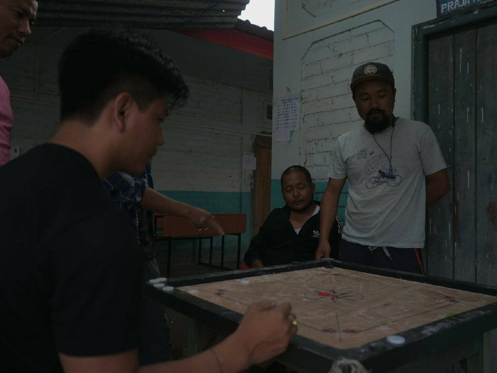 A group of men, displaced by the violence, play carrom inside a refugee camp in Imphal.