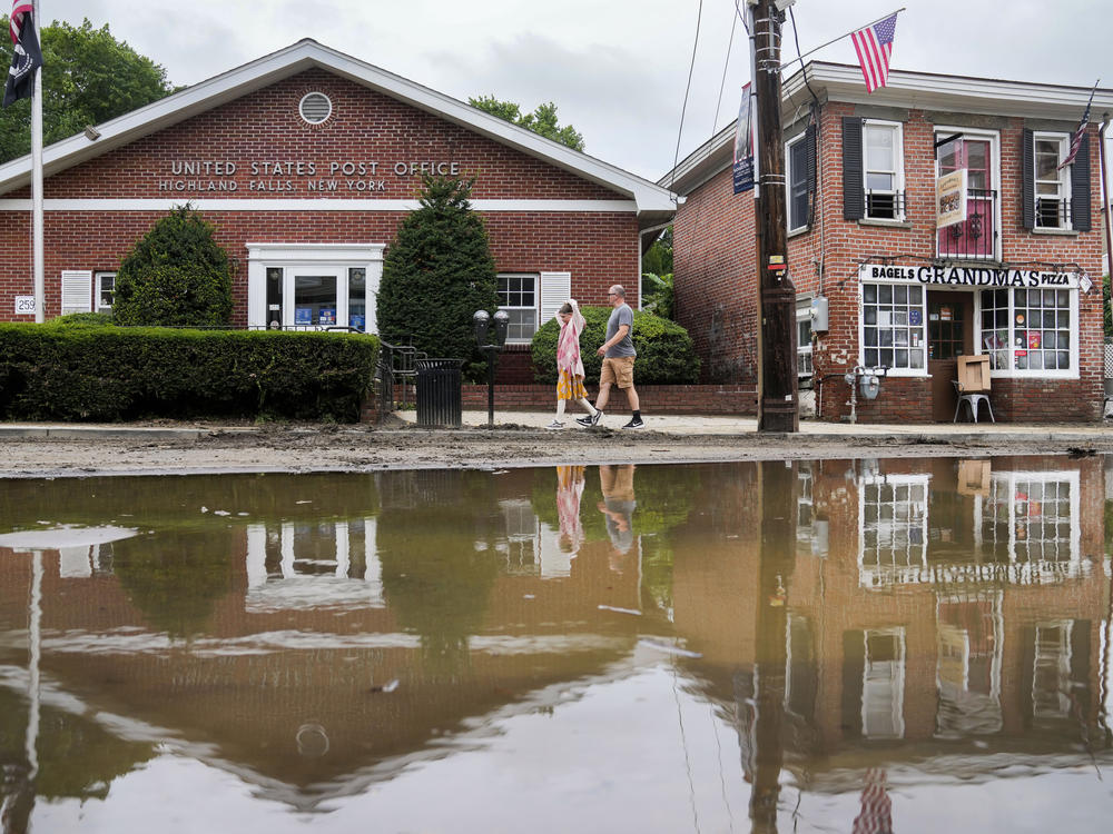 Pedestrians walk along Main Street in Highland Falls, N.Y. on Monday, July 10, after it was was damaged by flooding the previous day.