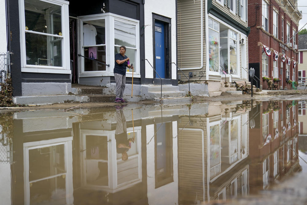Kathy Eason, a worker at the Center for Highland Falls, stands outside the organization's storefront after being trapped inside by floodwaters the previous day, Monday, July 10, in Highland Falls, N.Y.