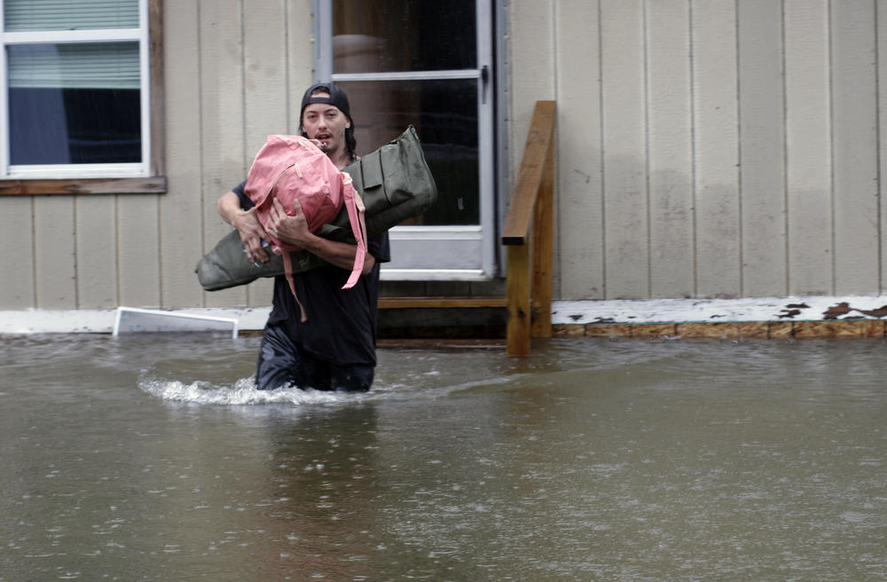 A man carries belongings through floodwaters from a home in Bridgewater, Vt., on Monday, July 10.