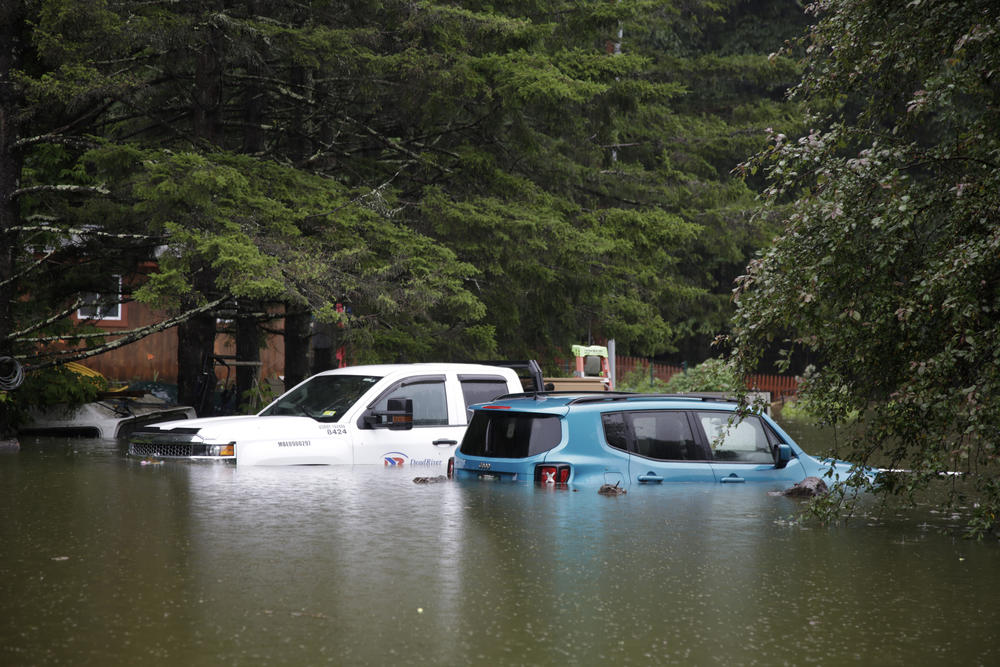 Floodwaters submerge parked vehicles and threaten homes near the Ottauquechee River on Monday, July 10, in Bridgewater, Vt.